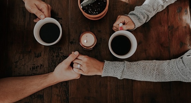 couple holding hands over coffee