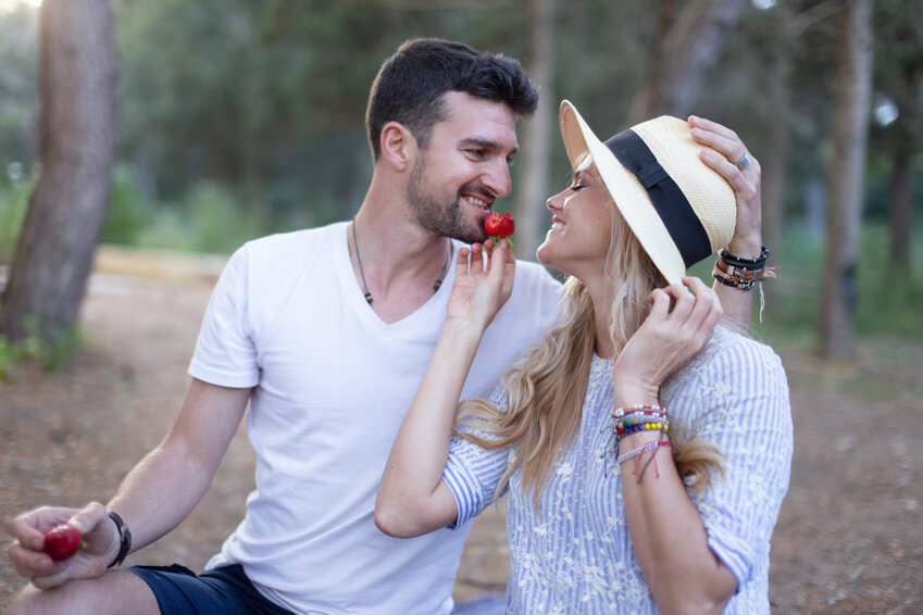 Cute couple sharing strawberries in the forest