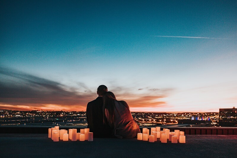 Couple sitting on a roof with candles in the evening