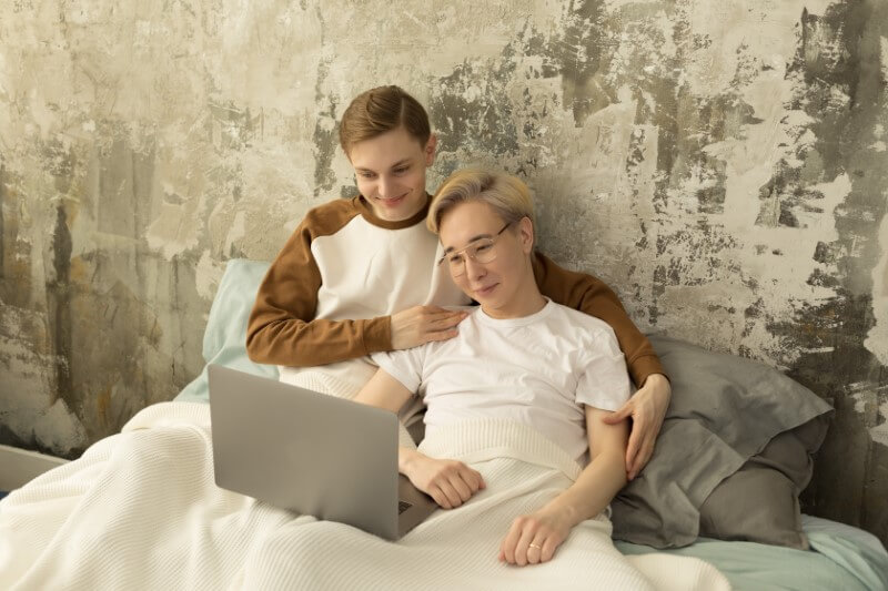 gay couple watches movie on laptop while in bed