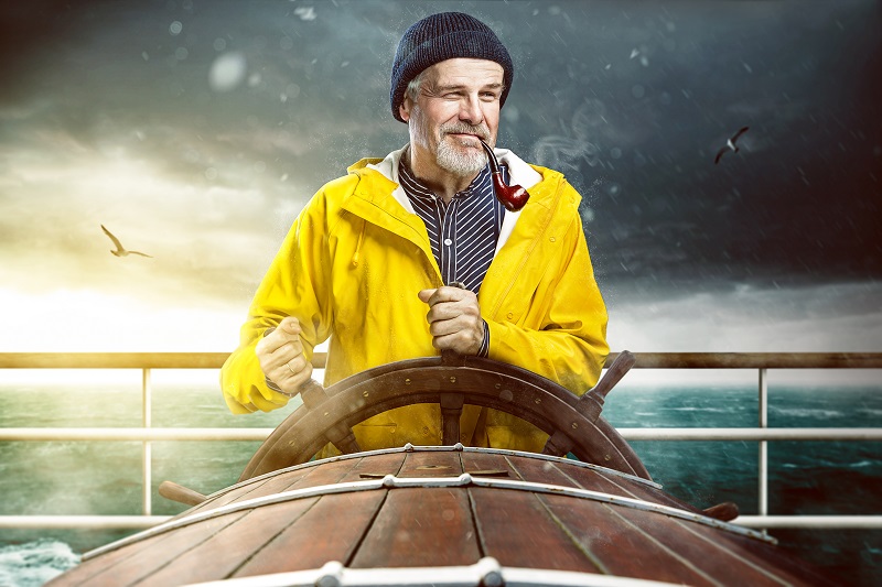 Charming sea captain steering a boat at sea