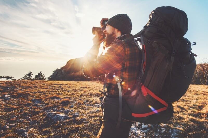 backpacker takes a photo in the sunset