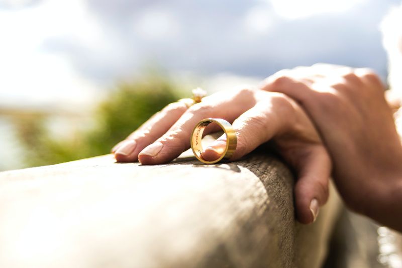 male hand grabbing a woman's wrist while her wedding ring is slipping off her finger